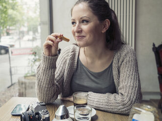 Lächelnde junge Frau mit Kamera in einem Cafe - TAMF000597