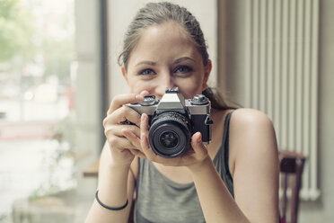 Portrait of smiling young woman hoding a camera - TAMF000600