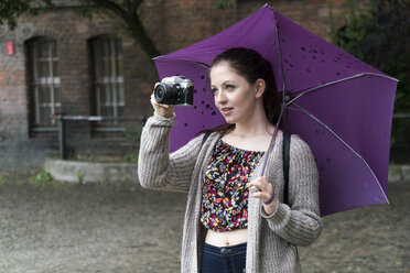 Junge Frau mit Kamera und Regenschirm im Freien - TAMF000608