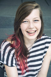 Porträt einer lachenden jungen Frau mit roter Haarsträhne - TAMF000610