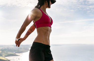 Female runner on beach with sports bra and shorts. Midsection