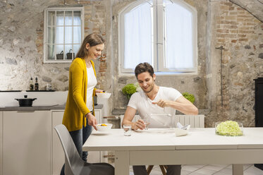 Couple in kitchen eating fruit salad - DIGF001154