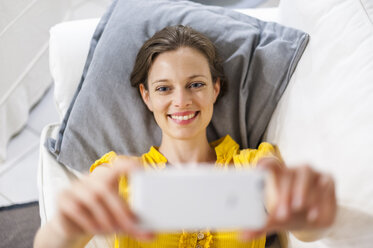 Frau auf der Couch liegend nimmt Selfie - DIGF001163