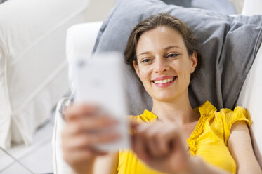 Frau auf der Couch liegend nimmt Selfie - DIGF001164