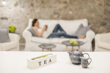 Woman sitting on couch, drinking tea - DIGF001170