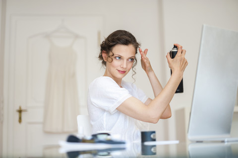 Frau macht sich zu Hause die Haare mit Haarspray, lizenzfreies Stockfoto