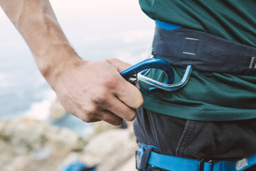 Close-up of climber placing a carabiner in his climbing harness - RAEF001453