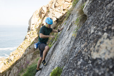 Young man climbing a rock wall - RAEF001476
