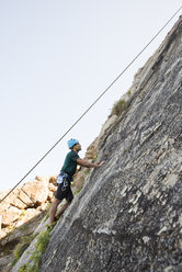 Junger Mann klettert an einer Felswand - RAEF001477