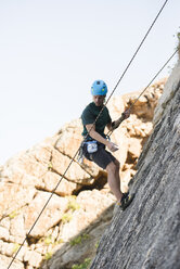 Young man climbing a rock wall - RAEF001480