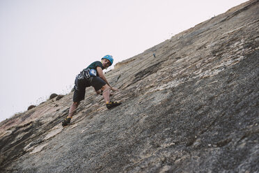 Junger Mann klettert an einer Felswand - RAEF001484