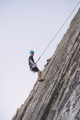 Junger Mann klettert an einer Felswand - RAEF001487