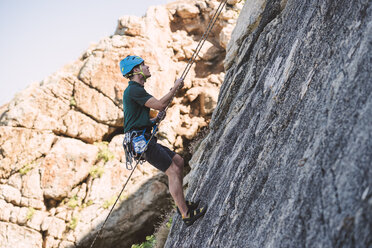 Young man climbing a rock wall - RAEF001489