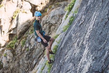 Junger Mann klettert an einer Felswand - RAEF001490