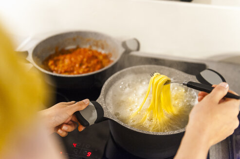 Frau bereitet Spaghetti vor und prüft, ob sie bereit zum Verzehr sind - DIGF001202
