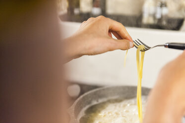 Frau bereitet Spaghetti vor und prüft, ob sie bereit zum Verzehr sind - DIGF001203
