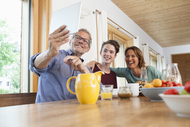 Happy family taking a selfie with tablet at dining table - RBF005160