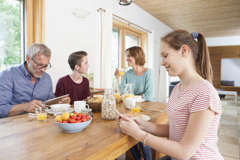 Familie nutzt tragbare Geräte beim Frühstück zu Hause - RBF005161