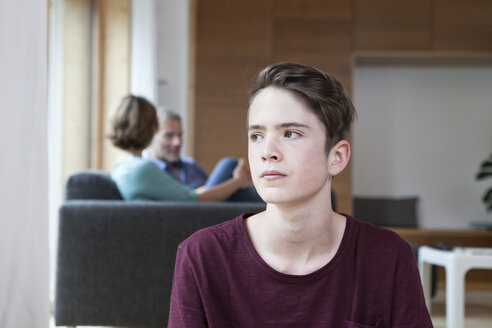 Nachdenklicher Teenager zu Hause mit Eltern im Hintergrund - RBF005170