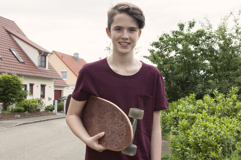 Porträt eines lächelnden Teenagers mit Skateboard - RBF005175