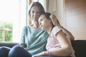 Mother comforting daughter sitting on sofa - RBF005176