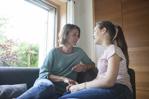 Mutter und Tochter sitzen auf dem Sofa und unterhalten sich - RBF005177