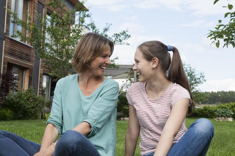 Happy mother and daughter sitting in garden stock photo