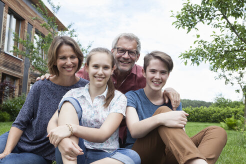 Porträt einer glücklichen Familie, die im Garten sitzt - RBF005190