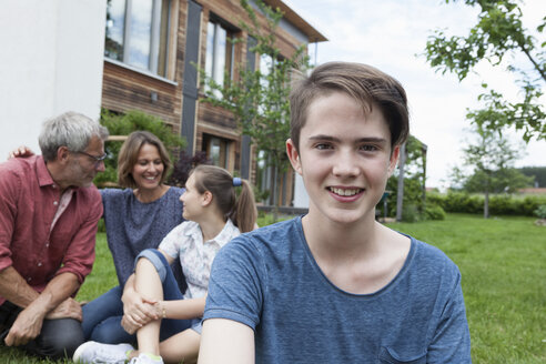 Porträt eines lächelnden Teenagers mit seiner Familie im Garten - RBF005193