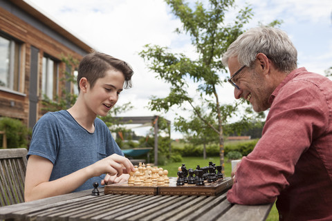 Vater und Sohn spielen Schach im Garten, lizenzfreies Stockfoto