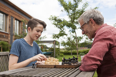 Father and son playing chess in garden - RBF005201