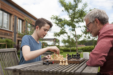 Vater und Sohn spielen Schach im Garten, lizenzfreies Stockfoto