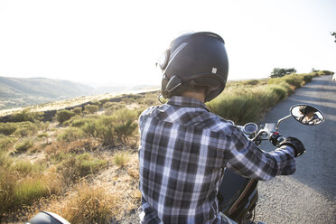 Rückenansicht eines Mannes auf einem Motorrad mit Blick auf die Aussicht - ABZF001143