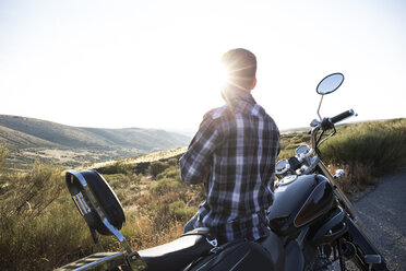 Man leaning on his motorbike looking at view in the evening twilight - ABZF001147