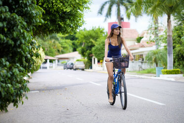 Mexico, Nayarit, young woman riding bicycle on street - ABAF002072