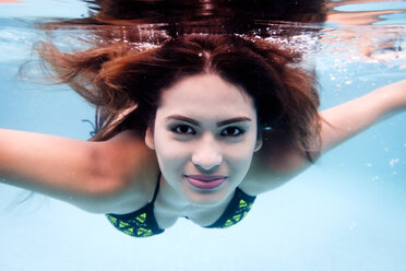 Portrait of smiling young woman underwater in a swimming pool - ABAF002074