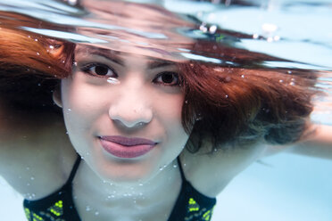 Porträt einer lächelnden jungen Frau unter Wasser in einem Schwimmbad - ABAF002075