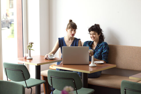 Zwei Freunde sitzen in einem Café und schauen auf einen Laptop - TSFF000087