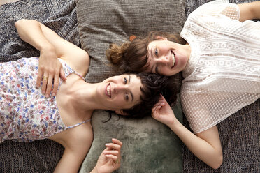 Zwei lächelnde Freunde liegen auf einer Decke auf dem Boden zu Hause - TSFF000109