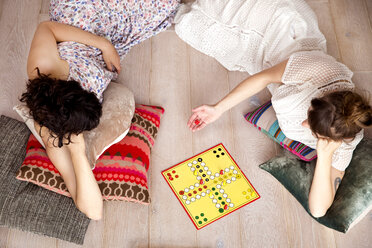 Draufsicht auf zwei beste Freunde, die zu Hause auf dem Boden liegen und Ludo spielen - TSFF000111