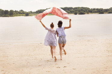 Back view of two friends running side by side on the beach holding cloth over their heads - TSFF000115