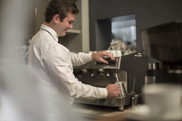 Junger Barista schäumt Milch aus einer Kanne auf - ZEF010052