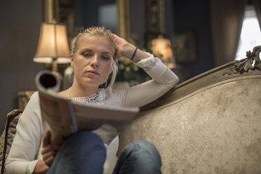 Young woman reading a magazine in a cafe - ZEF010057