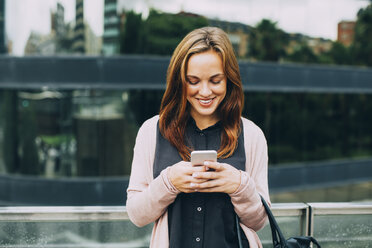 Smiling young woman looking at her cell phone - EBSF001708