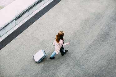 Draufsicht auf eine gehende Frau mit Gepäck auf Rädern - EBSF001711