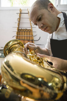 Instrumentenbauer bei der Demontage eines Saxophons während einer Reparatur - ABZF001162