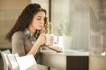 Junge Frau mit einer Tasse Kaffee in einem Kaffeehaus - ZOCF000138