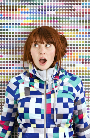 Young woman wearing patterned jacket in front of dotted wall stock photo