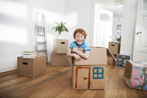 Happy boy looking out of a cardboard box in new apartment stock photo