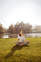 Frau mit geschlossenen Augen entspannt sich in Lotus-Yoga-Pose - MFF003058